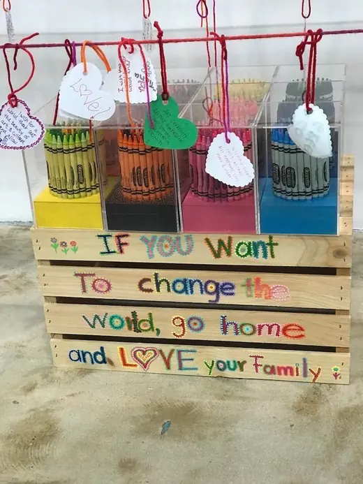 A decorated crate with the words If you want to change the world, go home and love your family